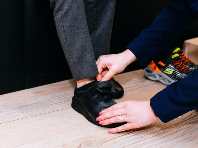 lady measuring kids feet inside shoe